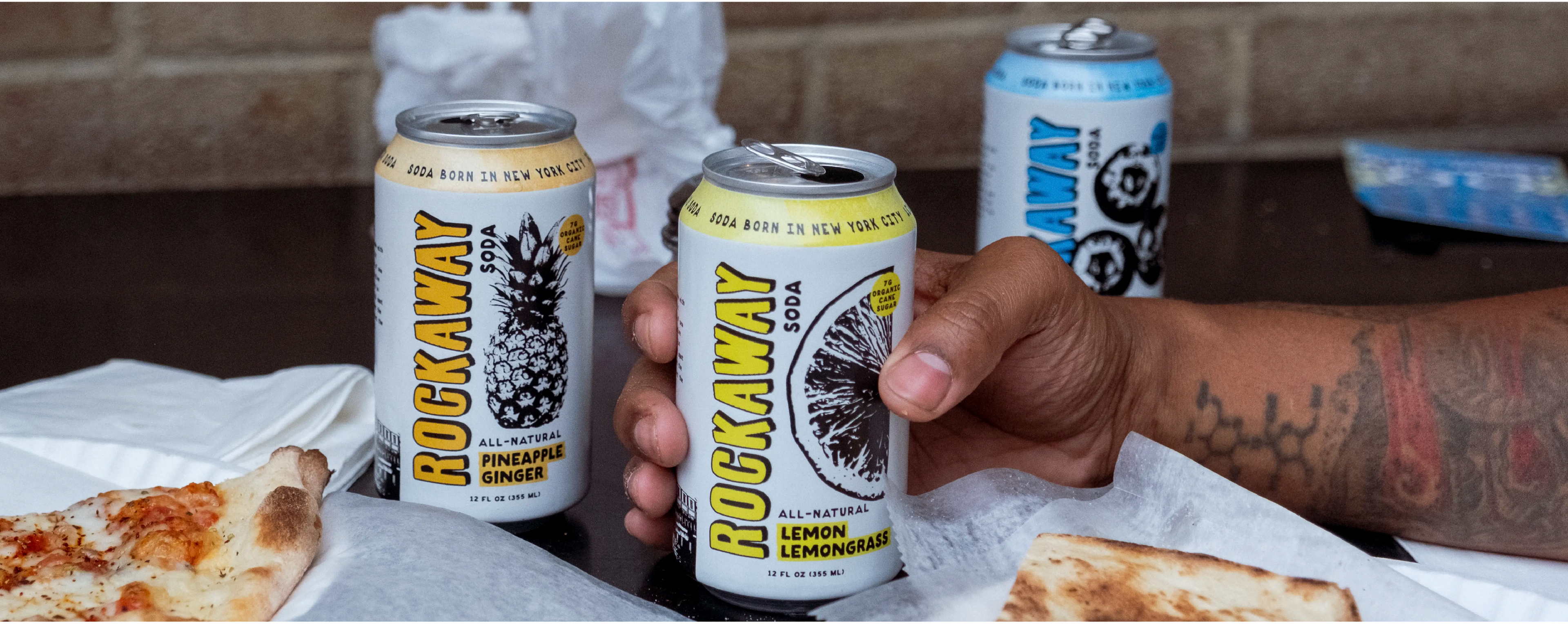 Rockaway Soda Cans on table with pizza.